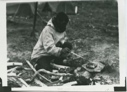 Image of Eskimo [Inuk, Ah-yah-o, "Bobbie"] frying seal meat on flat rock